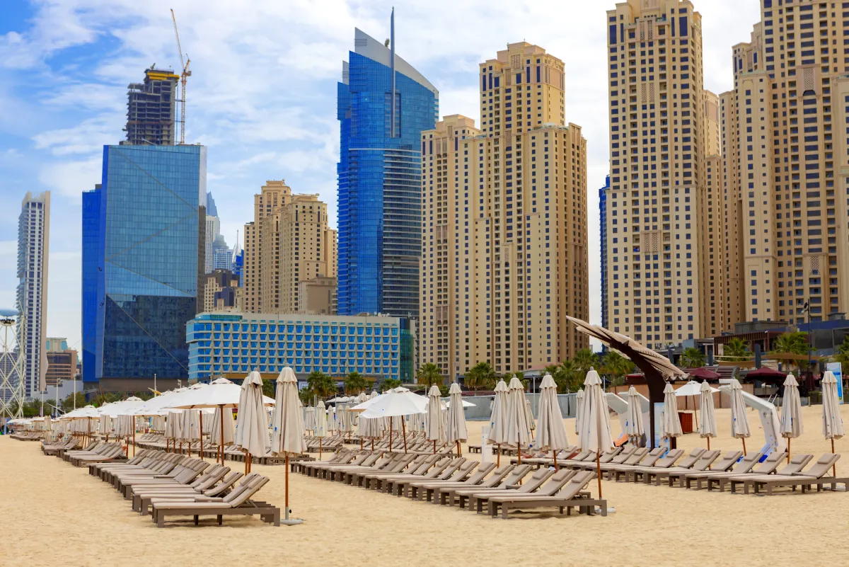 Liegen und Sonnenschirme am Strand von Jumeirah Beach Residence, dahinter die Hochhäuser