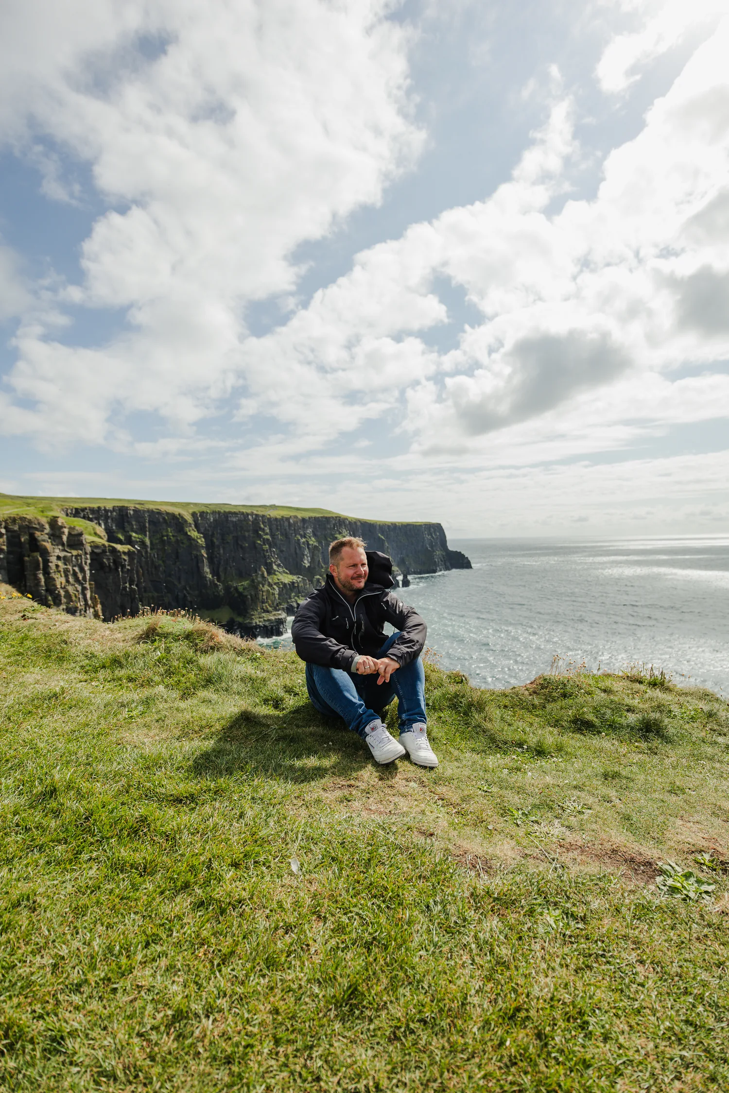 Benny sitzt am Rand der Cliffs of Moher und blickt aufs Meer