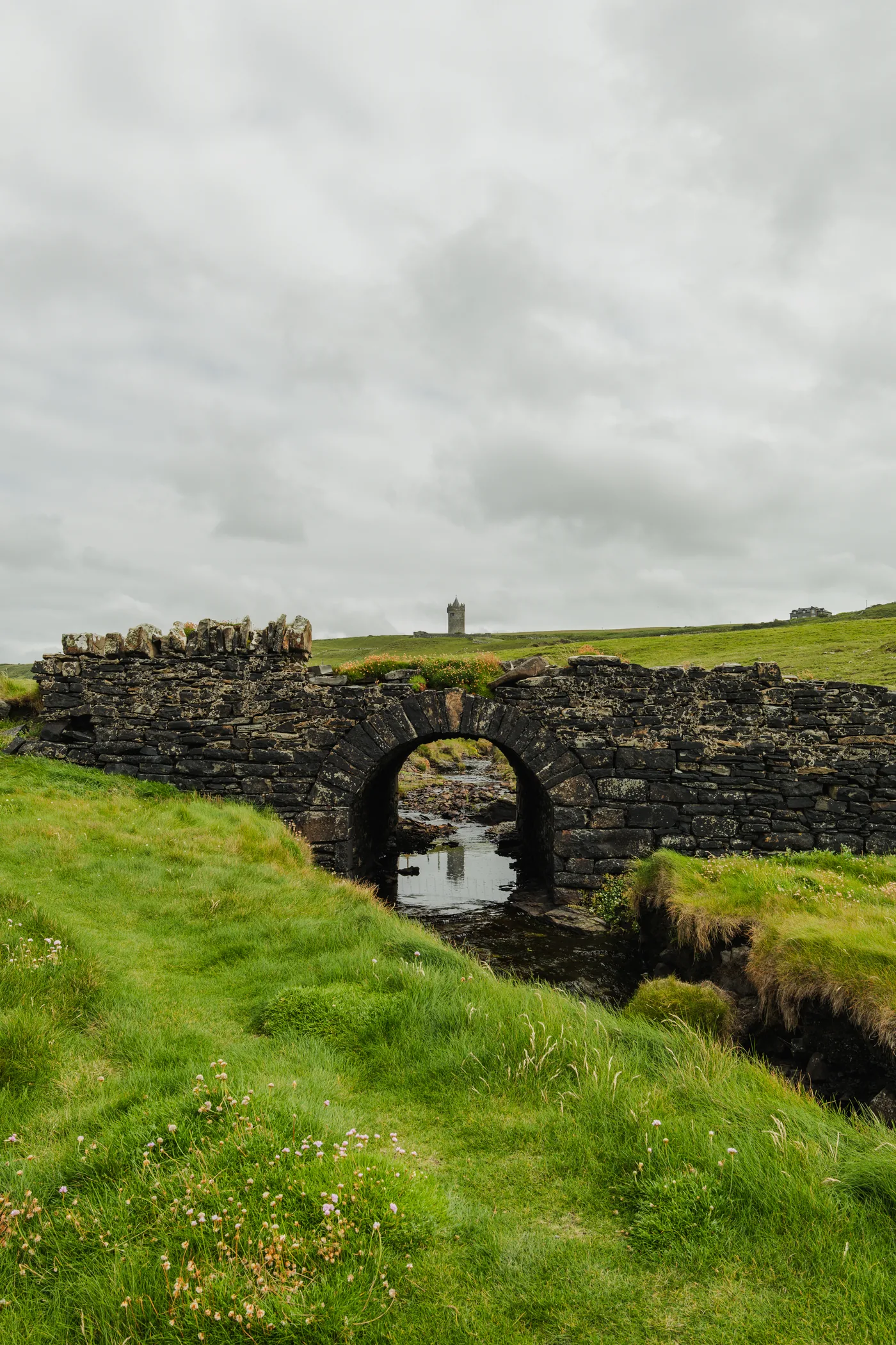 Alte Steinbogenbrücke bei Doolin mit Doonagore Castle im Hintergrund