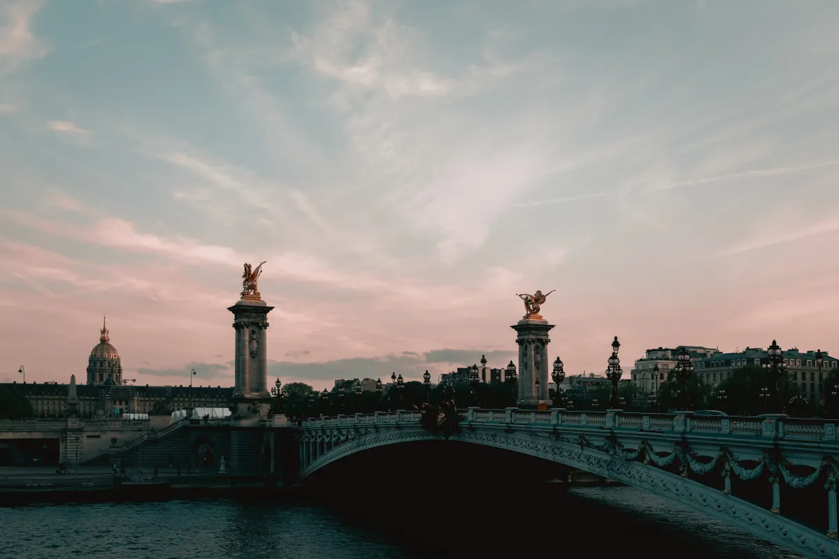 Die Pont Alexandre III über der Seine in der Abenddämmerung, dahinter die Kuppel des Invalidendoms