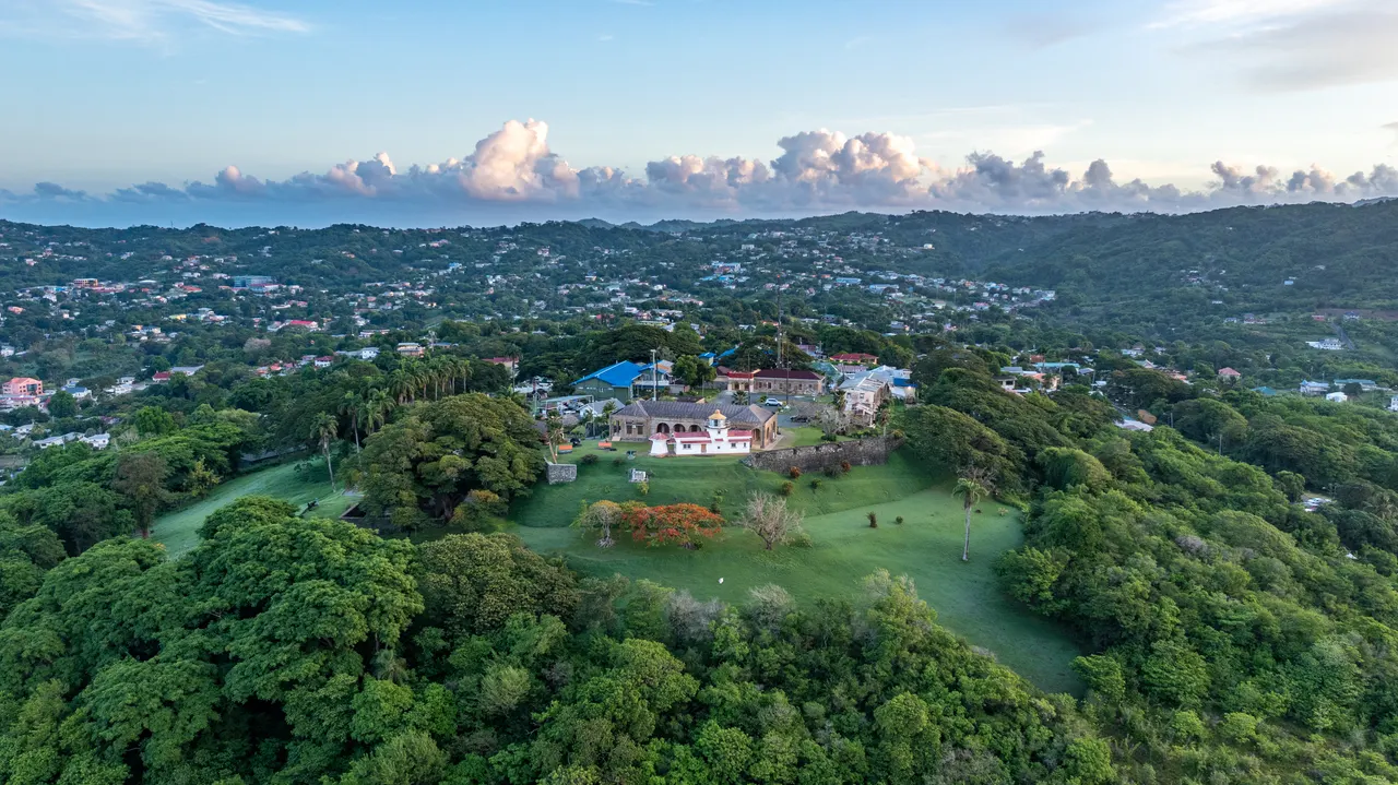 Grüne Hügel mit Villa über der Küste von Tobago aus der Luft